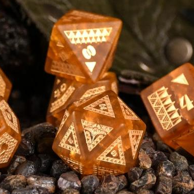 A set of Polynesian Lava Glass dice with Polynesian designs engraved on them, displayed on a bed of dark pebbles.