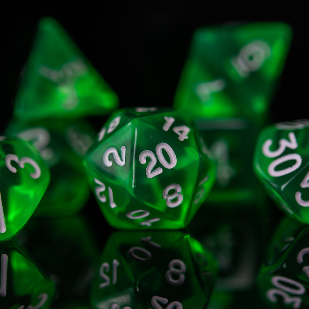 A set of green acrylic dice with engraved numbers. The dice include a D4, D6, D8, two D10s, D12, and D20, arranged on a reflective surface.