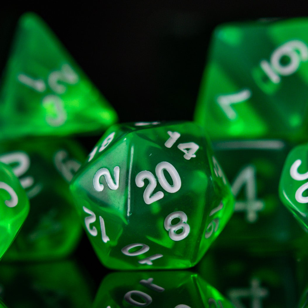 A set of green acrylic dice with engraved numbers. The dice include a D4, D6, D8, two D10s, D12, and D20, arranged on a reflective surface.