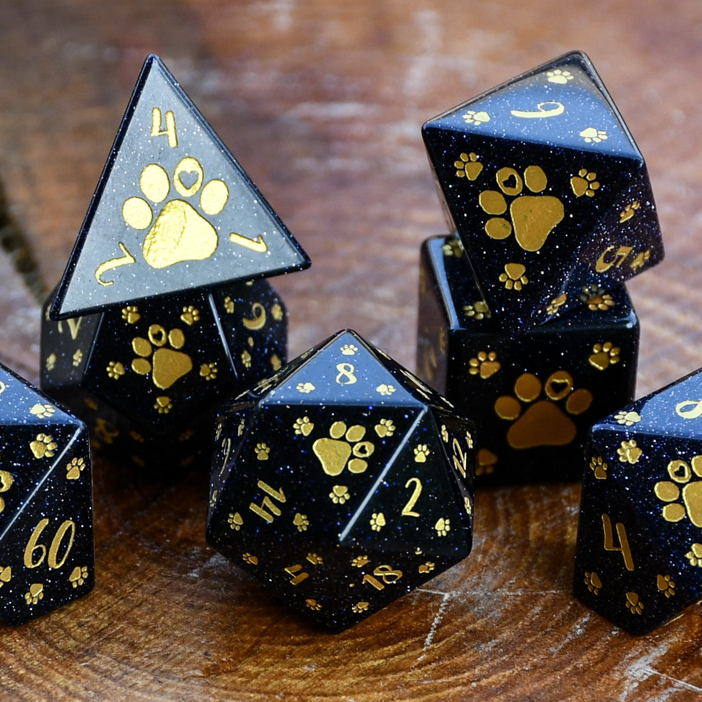 Puppy Paws Blue Sandstone Dice Set with gold paw prints and numbers on a wooden surface