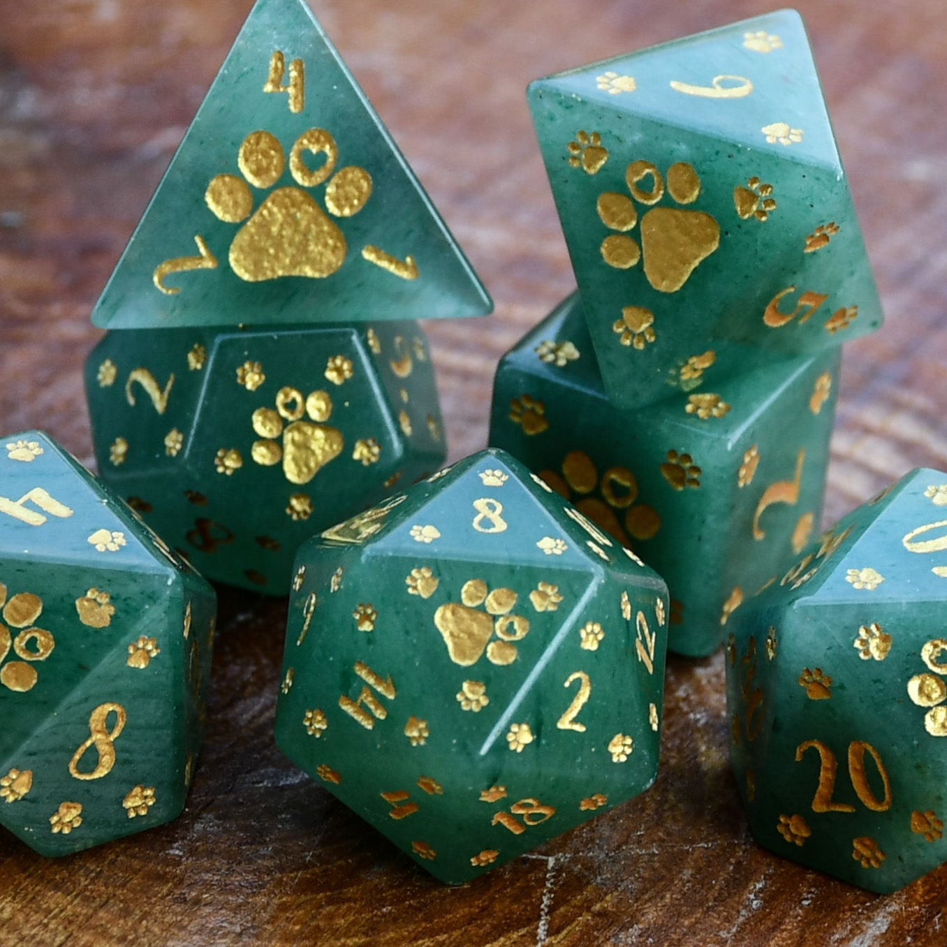 Set of green dice with gold paw prints on a wooden surface