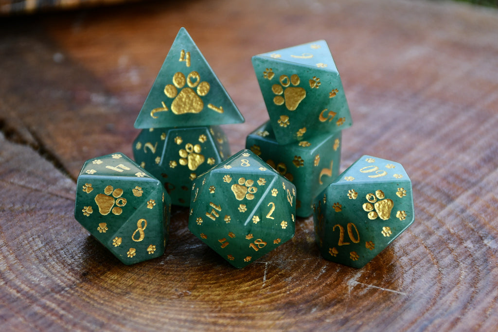 Set of green dice with gold paw prints on a wooden surface