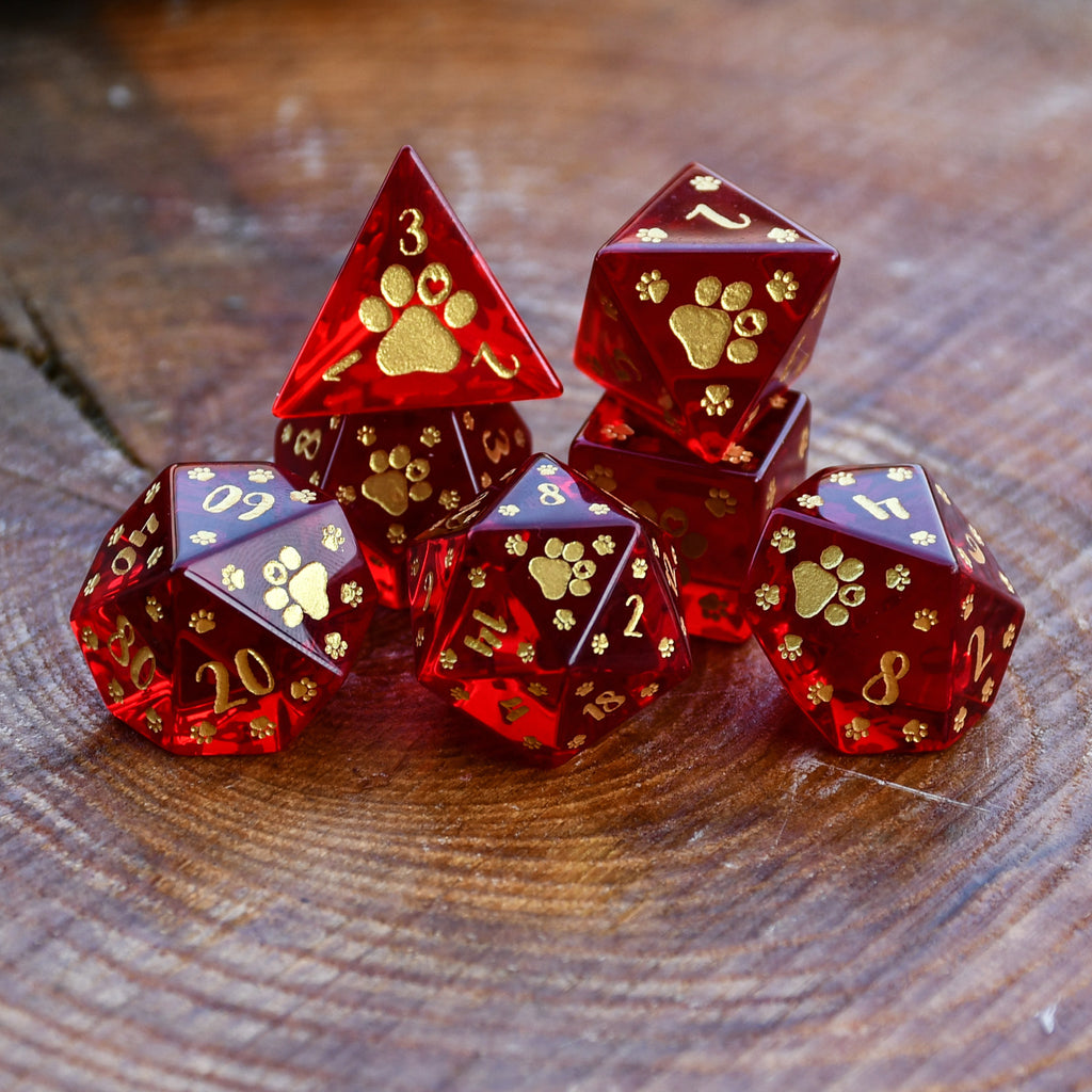 Puppy Paws Red Glass Dice Set with gold paw prints and numbers on a wooden surface