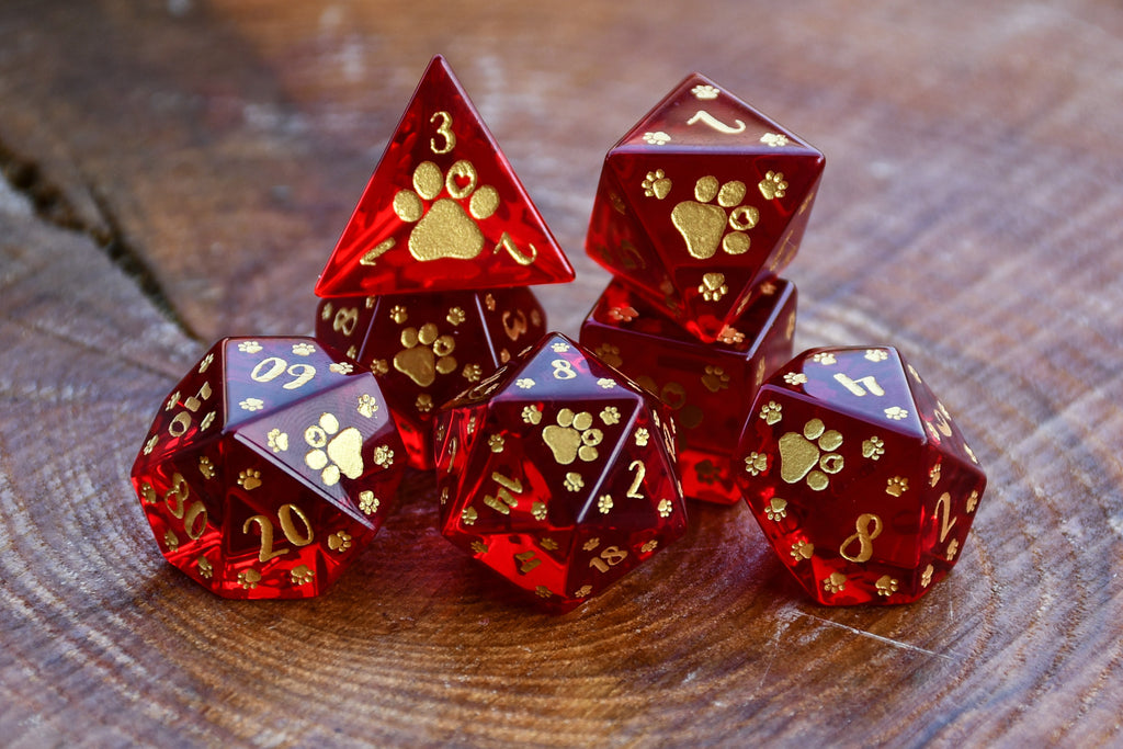 Puppy Paws Red Glass Dice Set  with gold paw prints on a wooden surface