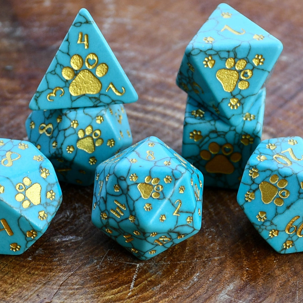 Puppy Paws Turquoise Dice Set with gold paw prints on a wooden surface