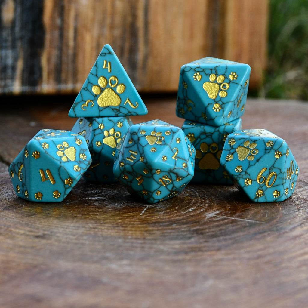 Puppy Paws Turquoise Dice Set with gold paw prints on a wooden surface