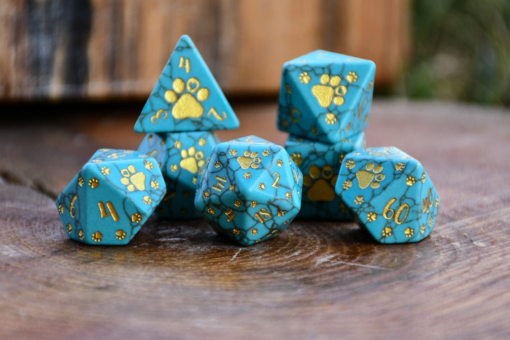 Puppy Paws Turquoise Dice Set with gold paw prints on a wooden surface