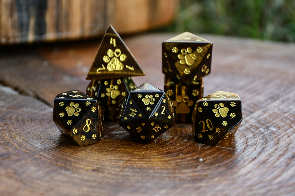 Puppy Paws Yellow Tiger Eye Dice Set with gold paw prints on a wooden surface