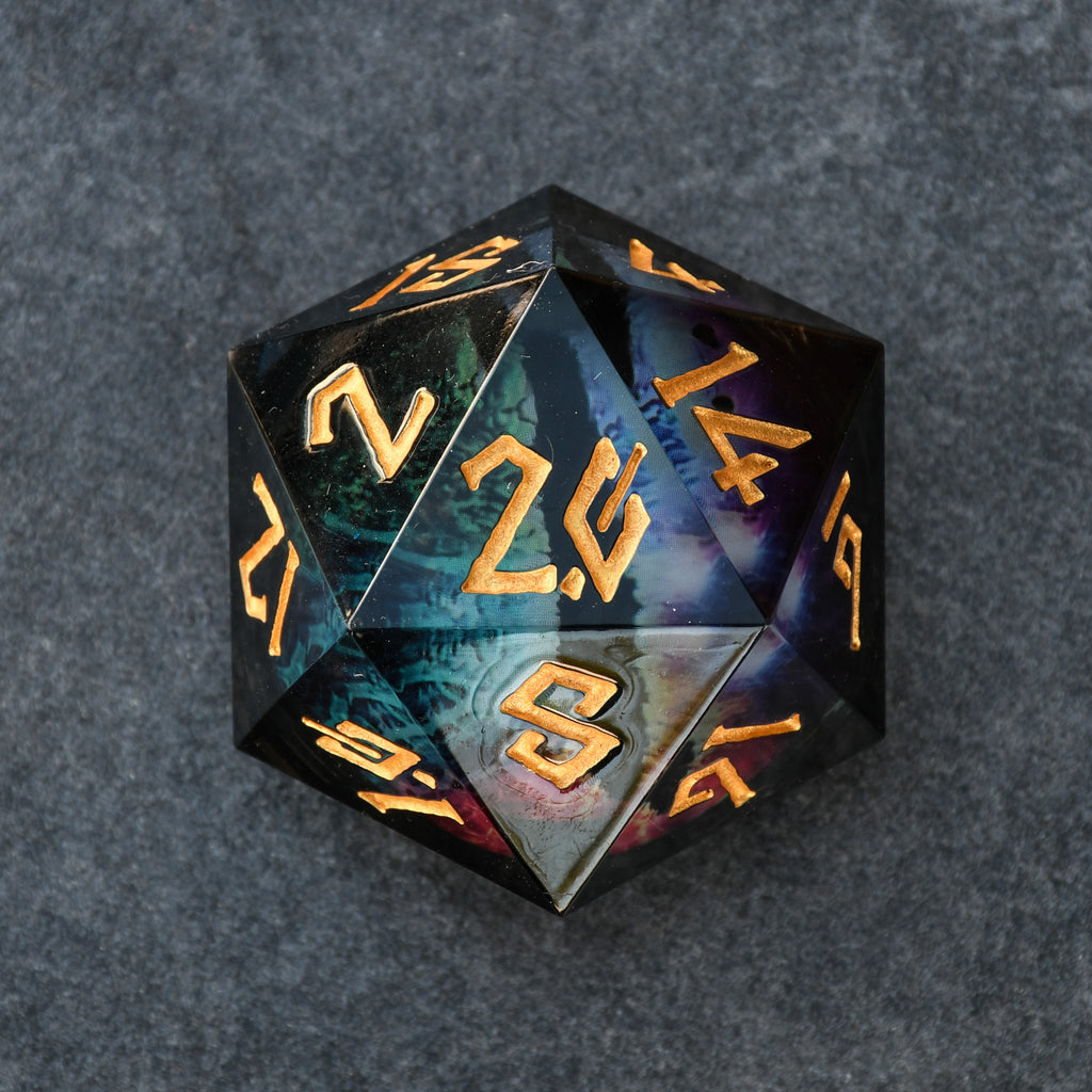 A 30mm black liquid core d20 dice with engraved gold numbers, featuring a floating rainbow dragons eye inside.