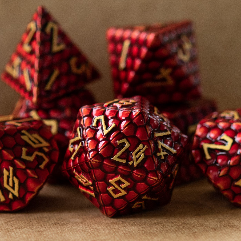 A collection of red dragon scale textured metal dnd dice with embossed numbers, featuring a dragon egg pattern, displayed on a textured background.