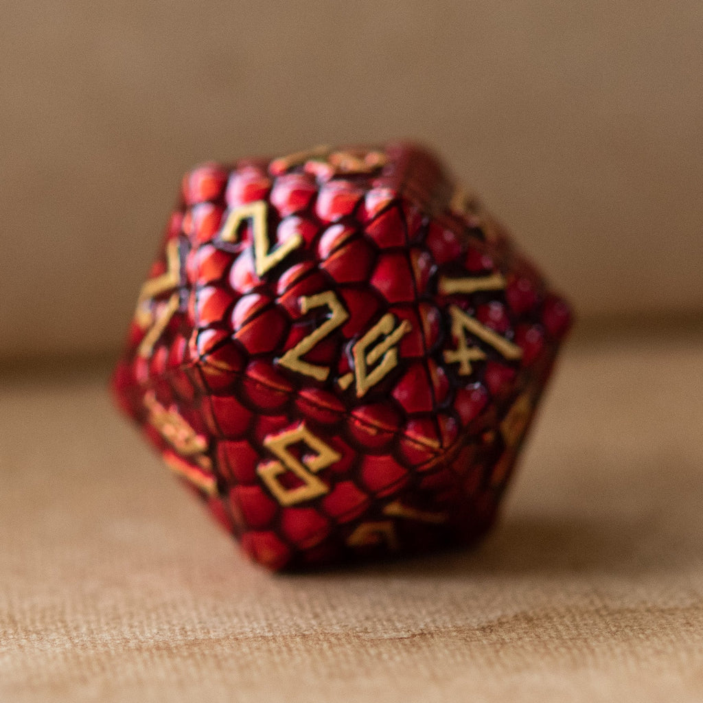 A collection of red dragon scale textured metal dnd dice with embossed numbers, featuring a dragon egg pattern, displayed on a textured background.