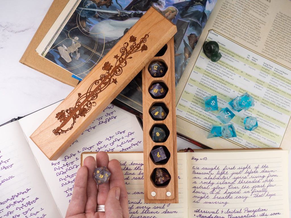 Wooden dice holder with engraved design on a table with gaming materials