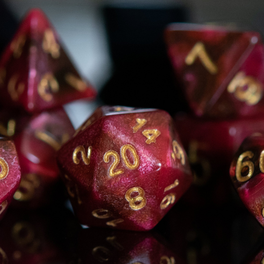 Set of red polyhedral dice with gold numbers on a reflective surface.