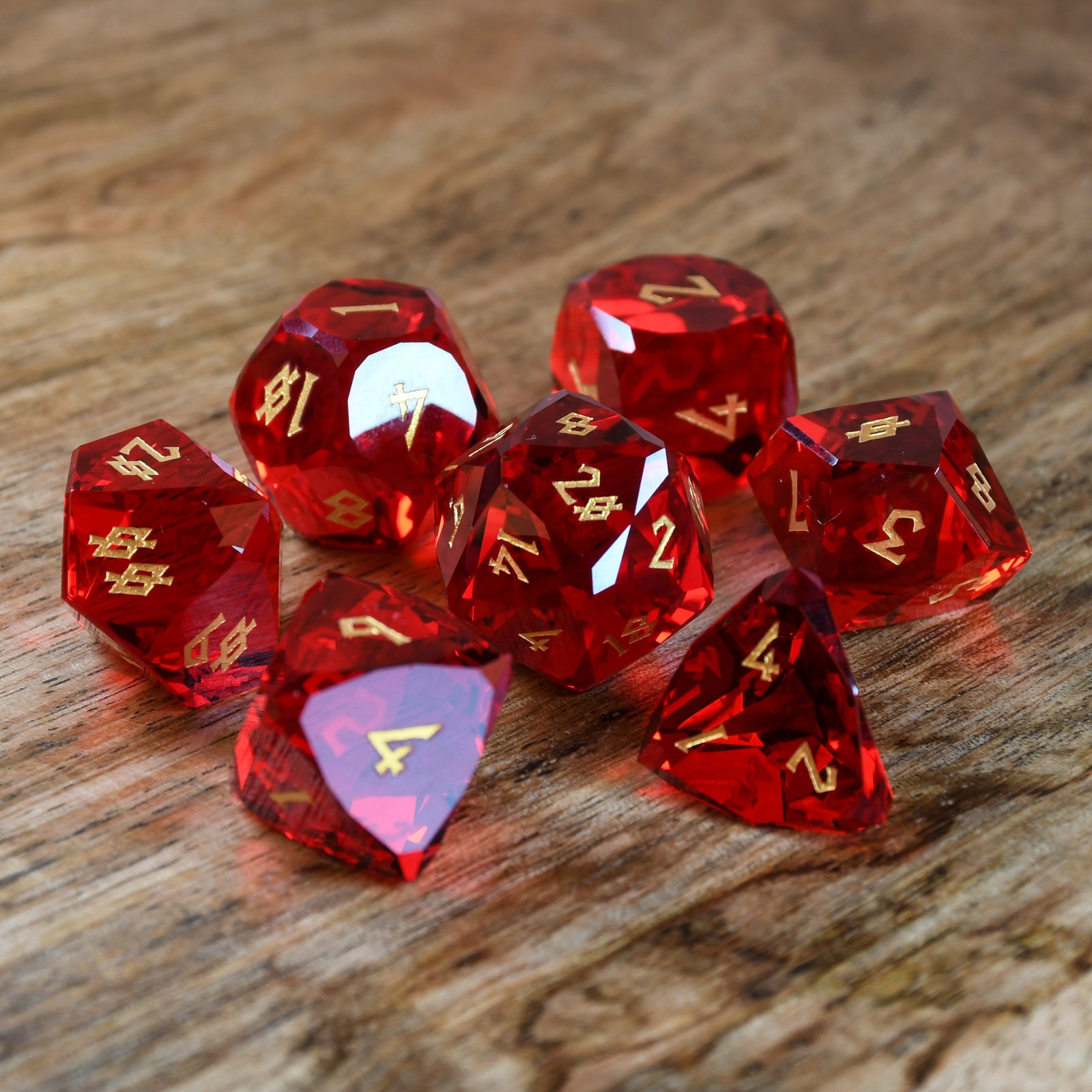 A set of multifaceted red glass dice with engraved numbers, placed on a wooden surface.