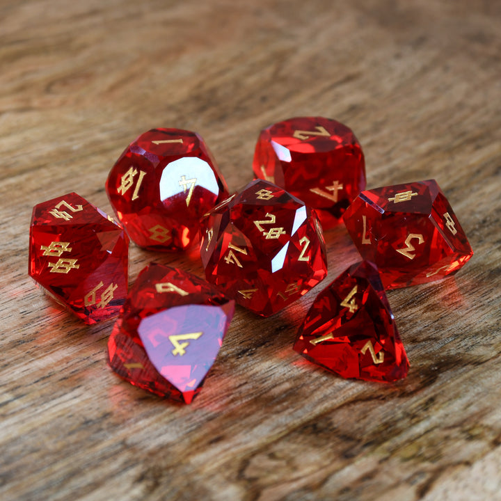 A set of multifaceted red glass dice with engraved numbers, placed on a wooden surface.