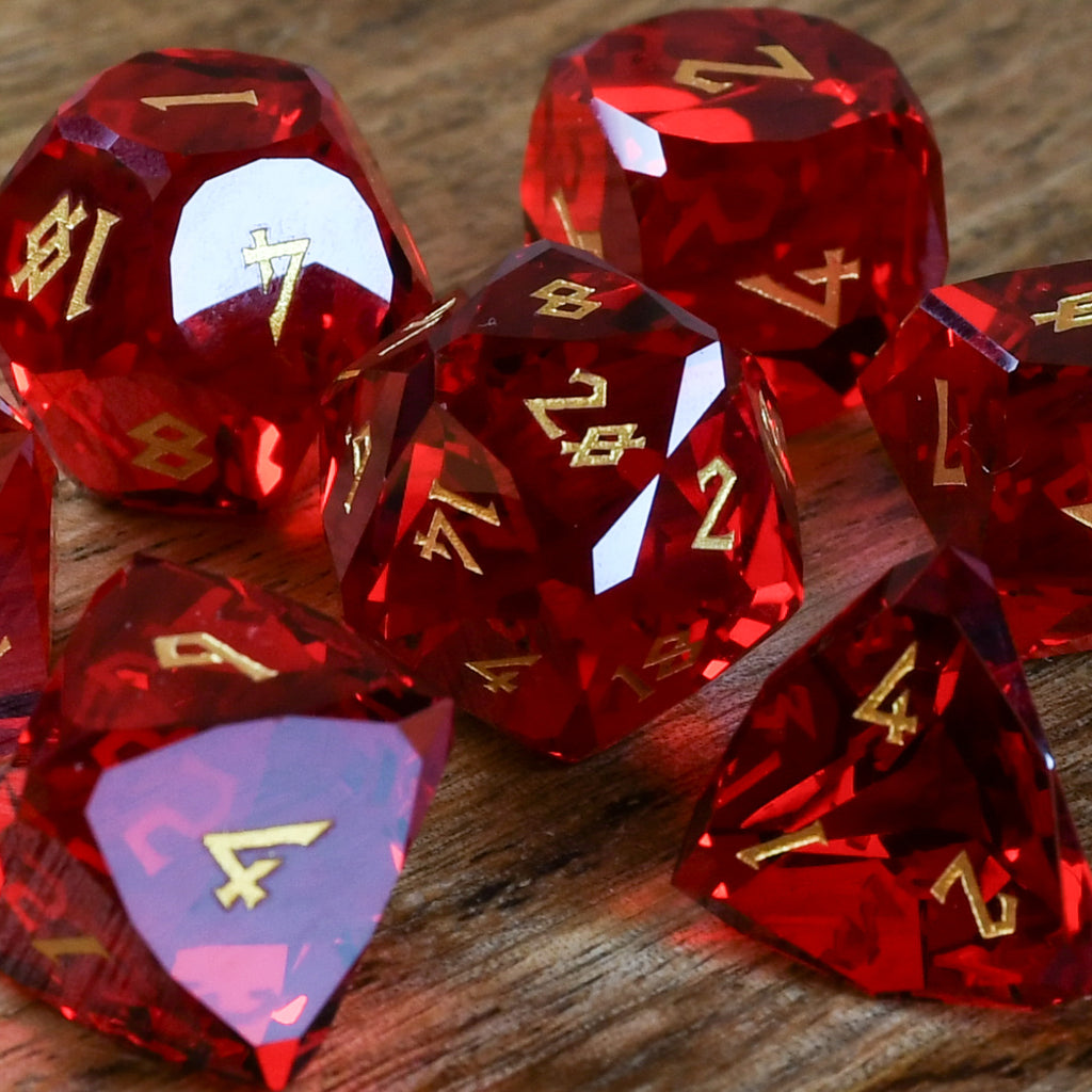 A set of multifaceted red glass dice with engraved numbers, placed on a wooden surface.