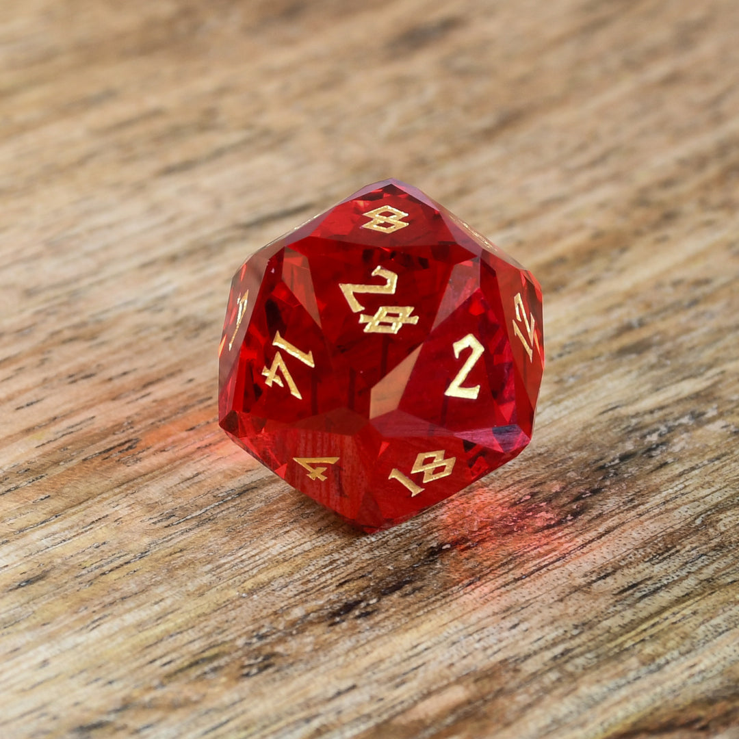 A set of multifaceted red glass dice with engraved numbers, placed on a wooden surface.