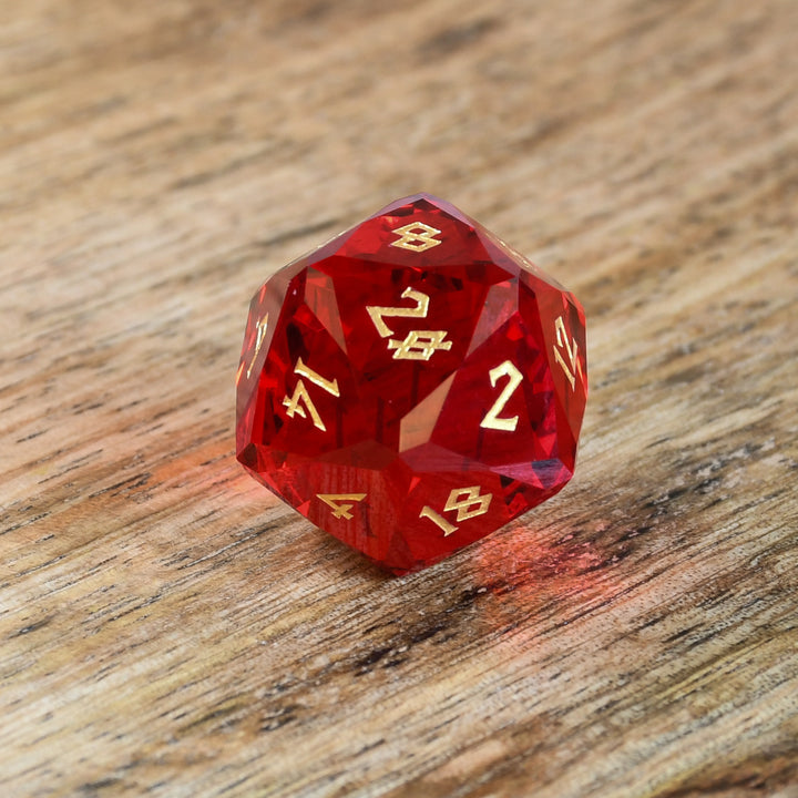 A set of multifaceted red glass dice with engraved numbers, placed on a wooden surface.