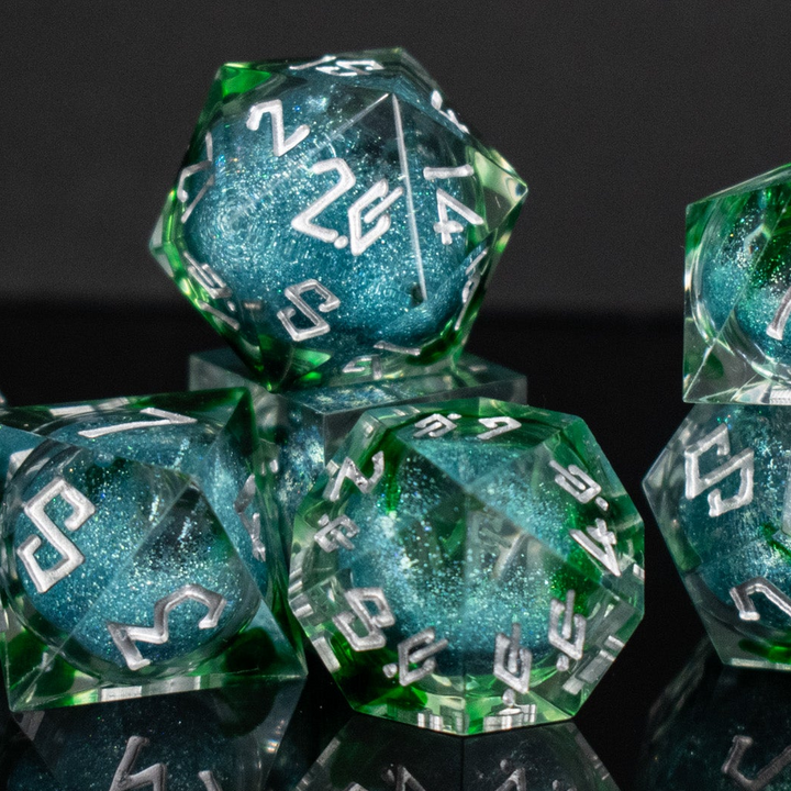 Set of green and blue polyhedral dice with white numbers on a reflective surface.