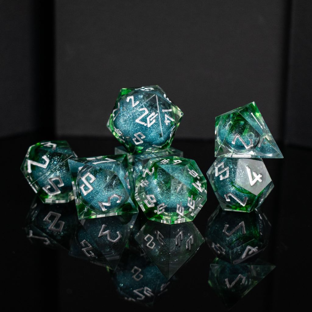 Set of green and blue polyhedral dice with white numbers on a reflective surface.