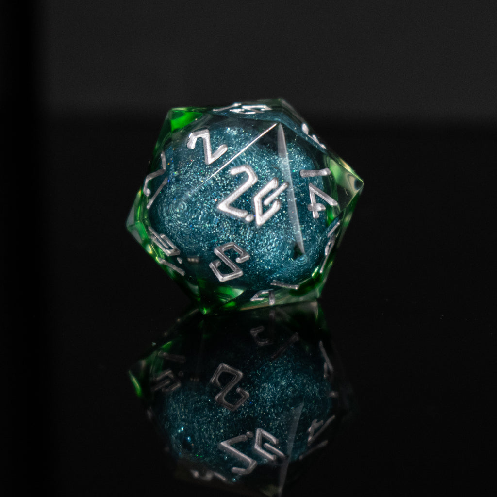 Set of green and blue polyhedral dice with white numbers on a reflective surface.