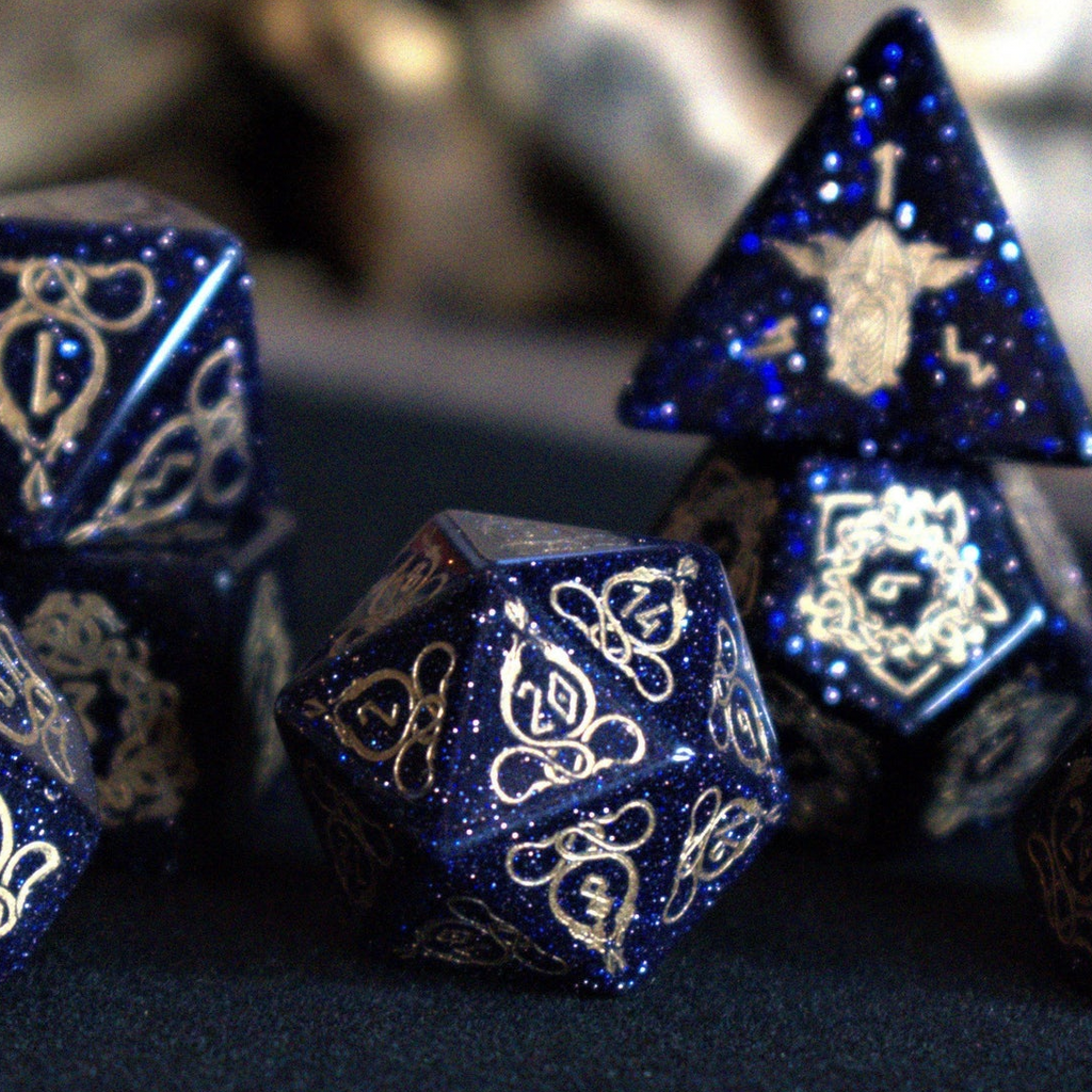 A close-up of hand-carved viking inspired blue sandstone ttrpg dice with engraved numbers and designs in gold