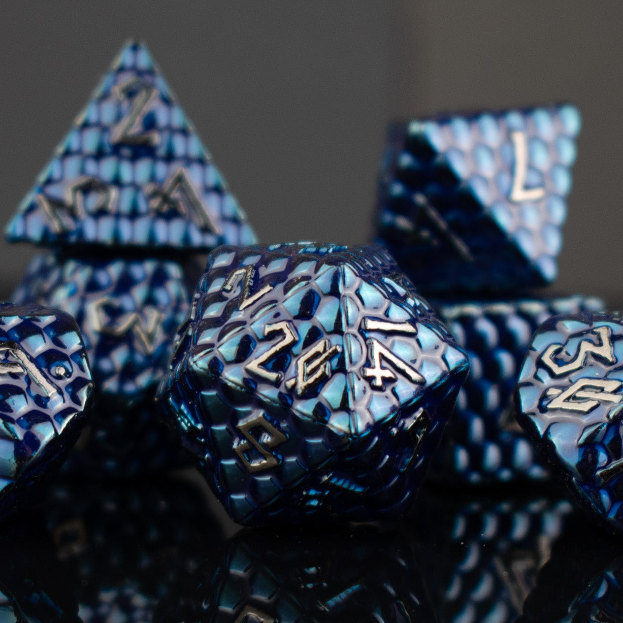 Blue polyhedral dice set with metallic text on a dark background