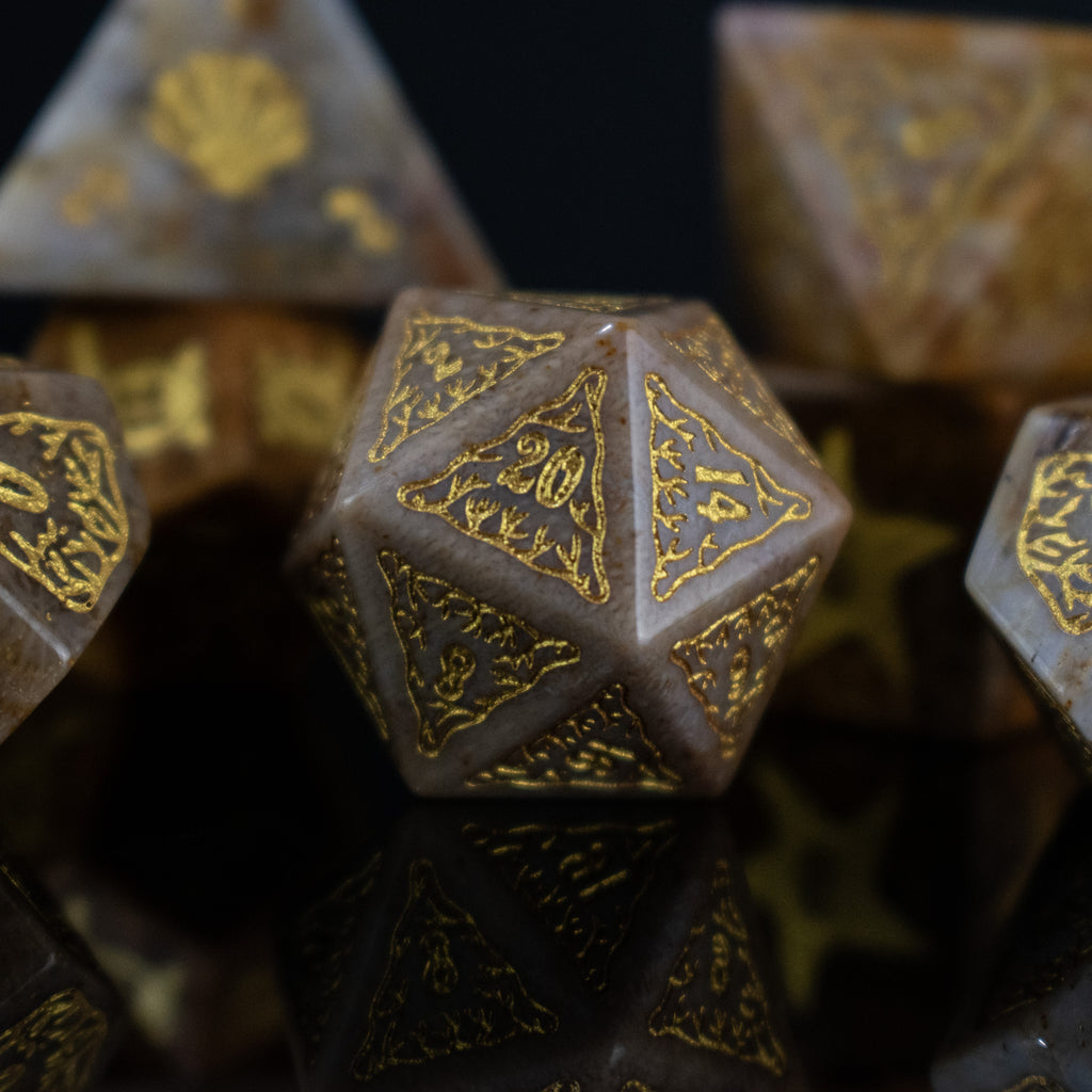 A set of hand-carved, fossil coral dice with engraved numbers, displayed on a reflective surface.