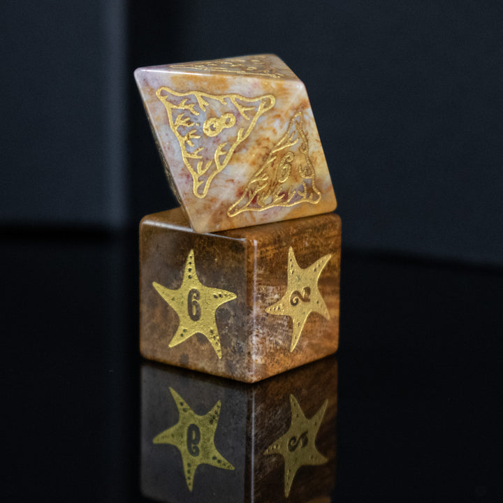A set of hand-carved, fossil coral dice with engraved numbers, displayed on a reflective surface.