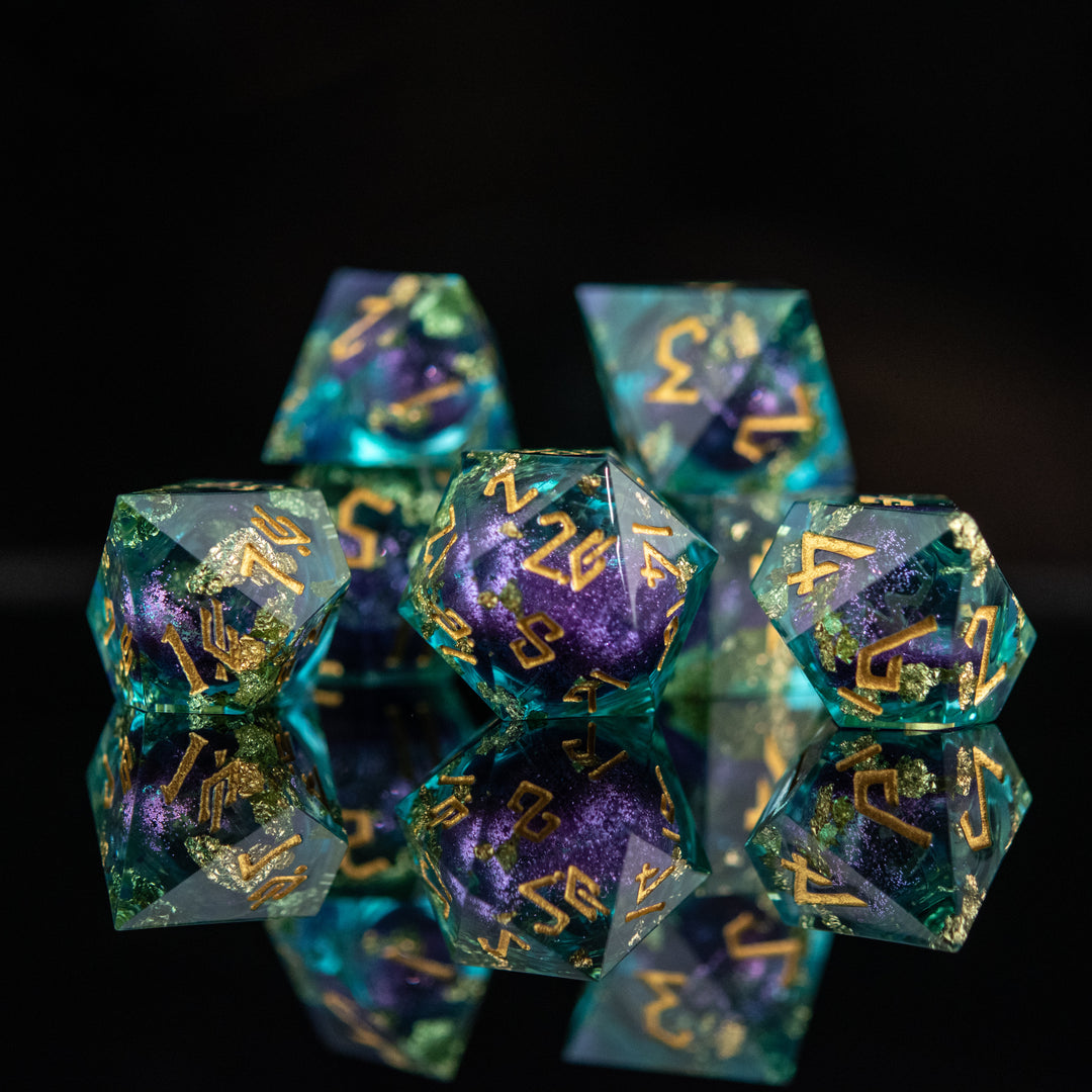 A set of resin core dice with purple and green colors, featuring engraved numbers and floating glitter, displayed on a reflective surface.