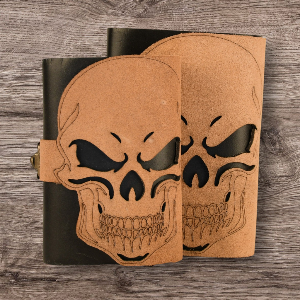 Two leather-bound books with skull designs on a wooden surface