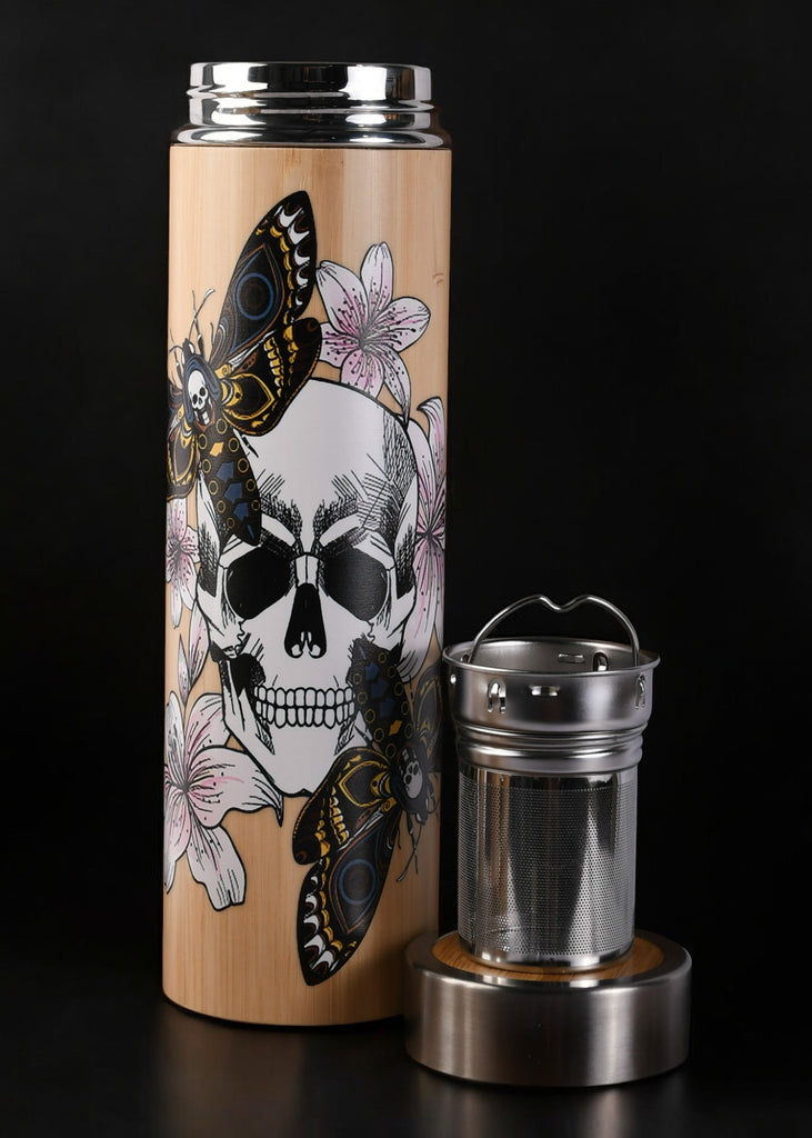 A stainless steel tea thermos with a graphic design of a skull, butterflies, and floral elements on the side. The thermos is accompanied by a removable steeper and is shown with the lid off.