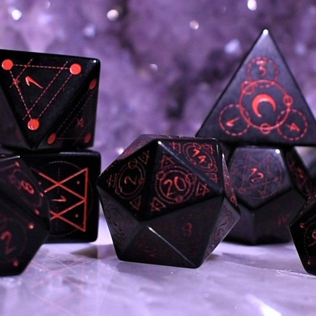 Black polyhedral dice with red numbering and symbols on a textured surface