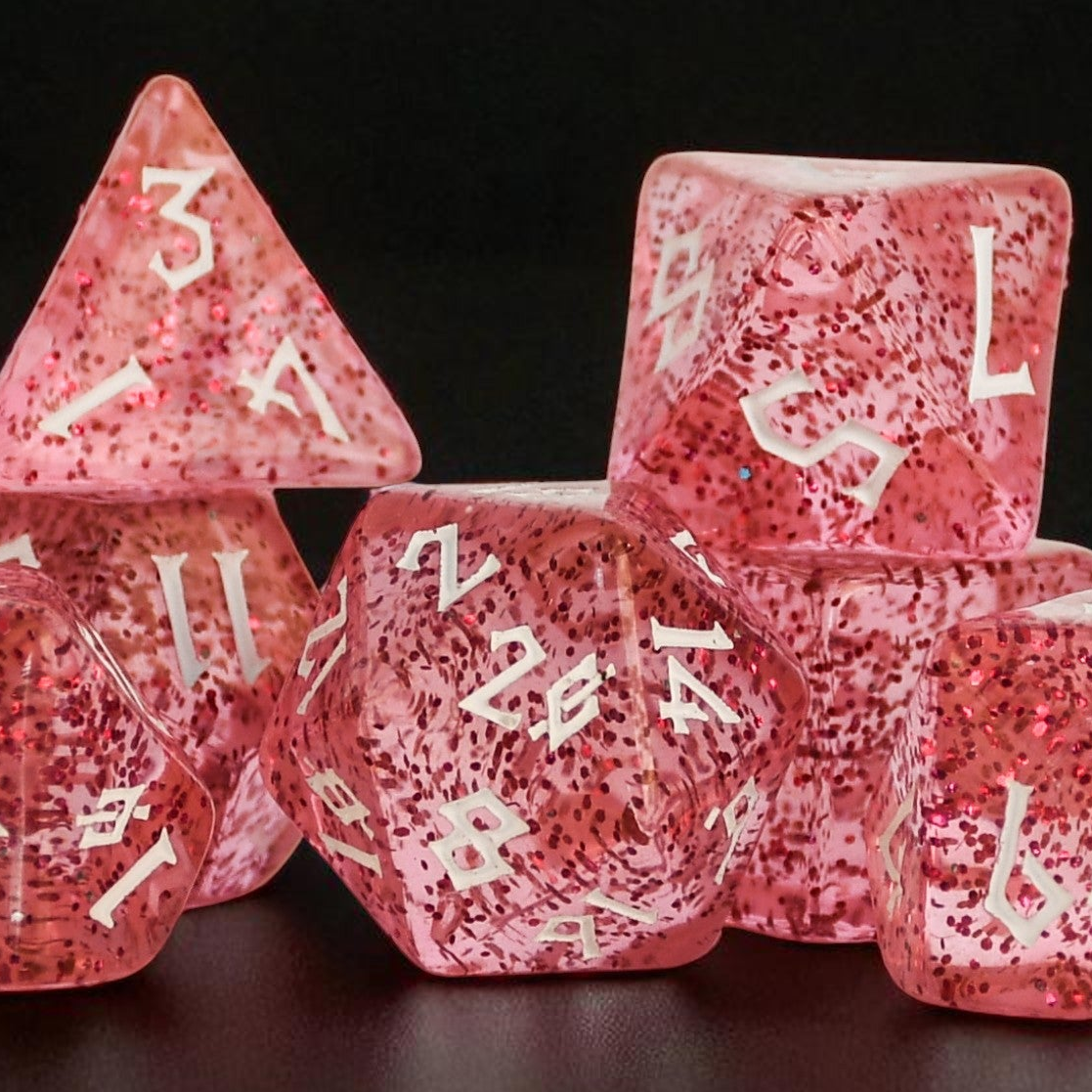 Pink acrylic dice set with glitter inside and white numbers in a clear nordic style font