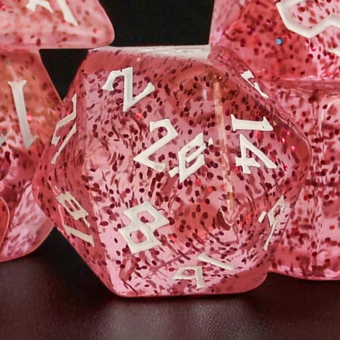 Pink acrylic dice set with glitter inside and white numbers in a clear nordic style font
