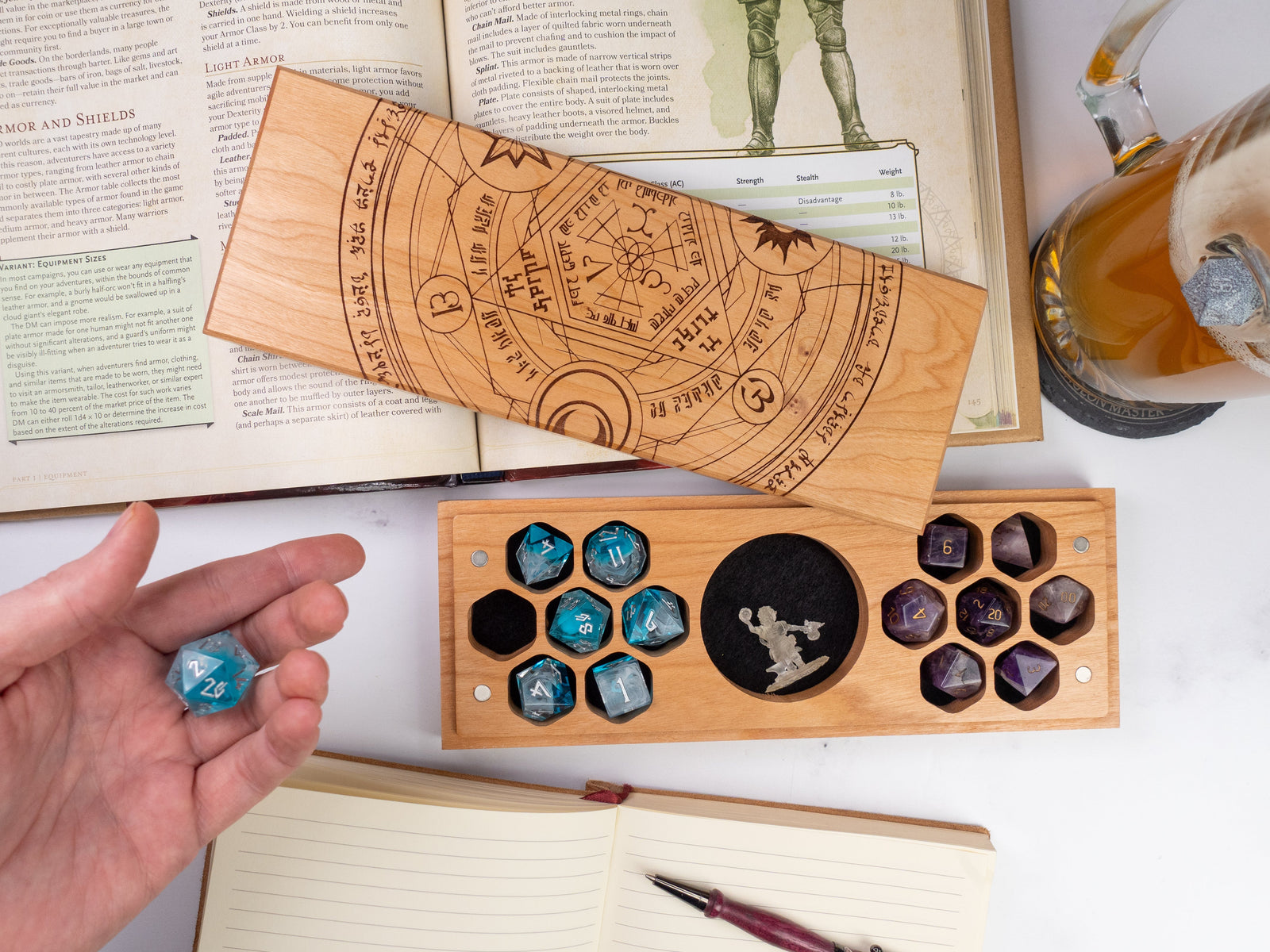 A wooden dice vault with an intricate etched design featuring an arcane summoning circle and various symbols, lying on a flat surface.