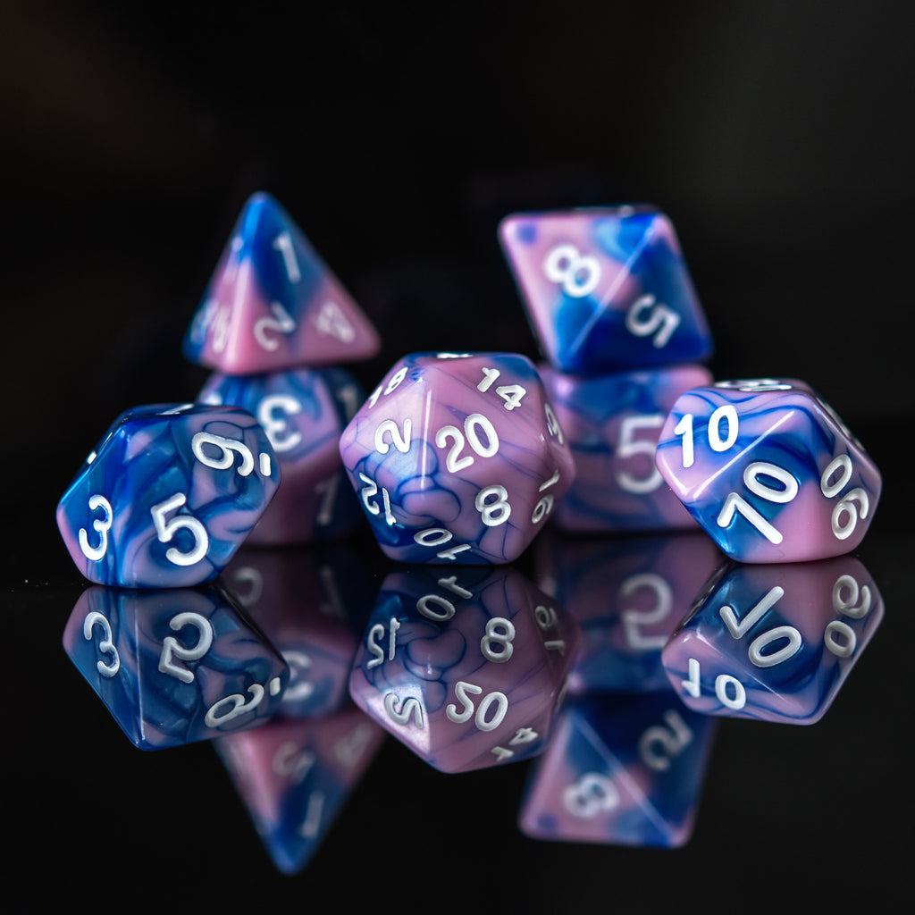 A set of hand-carved blue and pink acrylic dice with engraved numbers, displayed on a reflective surface.