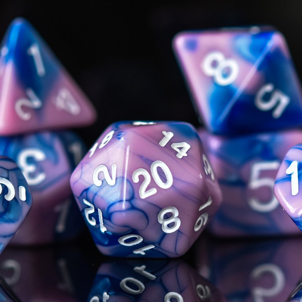 A set of hand-carved blue and pink acrylic dice with engraved numbers, displayed on a reflective surface.