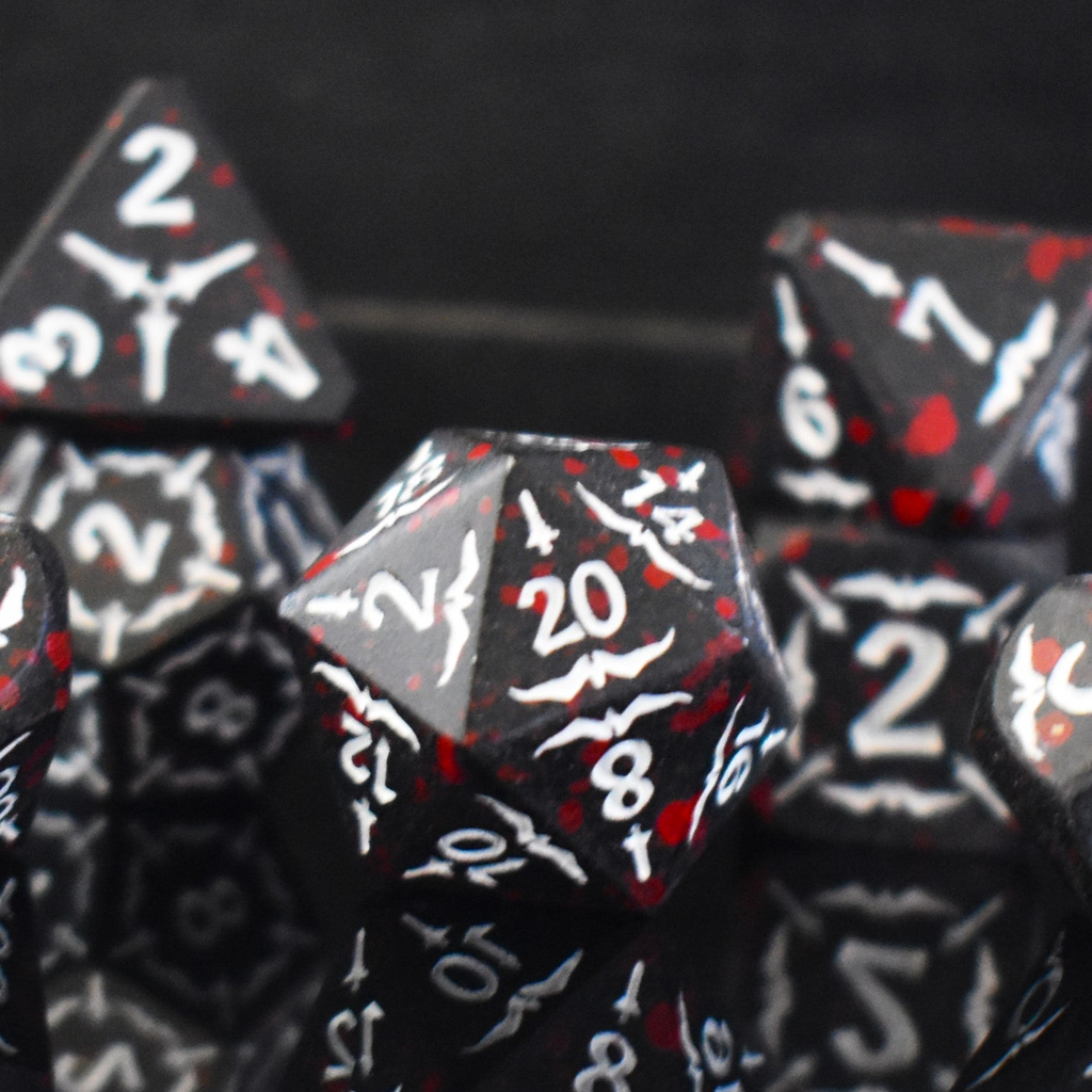 A set of black metal polyhedral dice with blood splatter across them and white numbering and sword details for tabletop gaming and board games