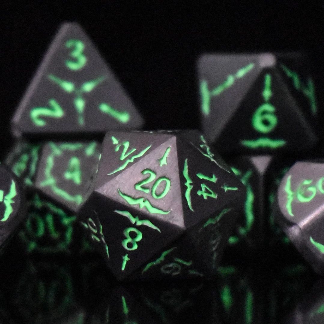 A set of glow-in-the-dark metal dnd dice with engraved numbers and swords, including various shapes such as a d4, d6, d8, d10, d12, and d20, displayed on a black background.
