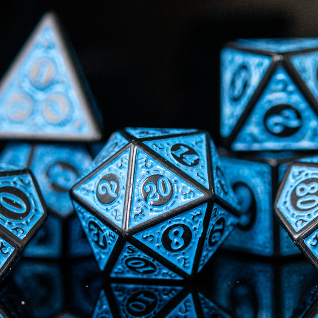 A set of blue acrylic ttrpg dnd dice with engraved numbers, displayed on a reflective surface