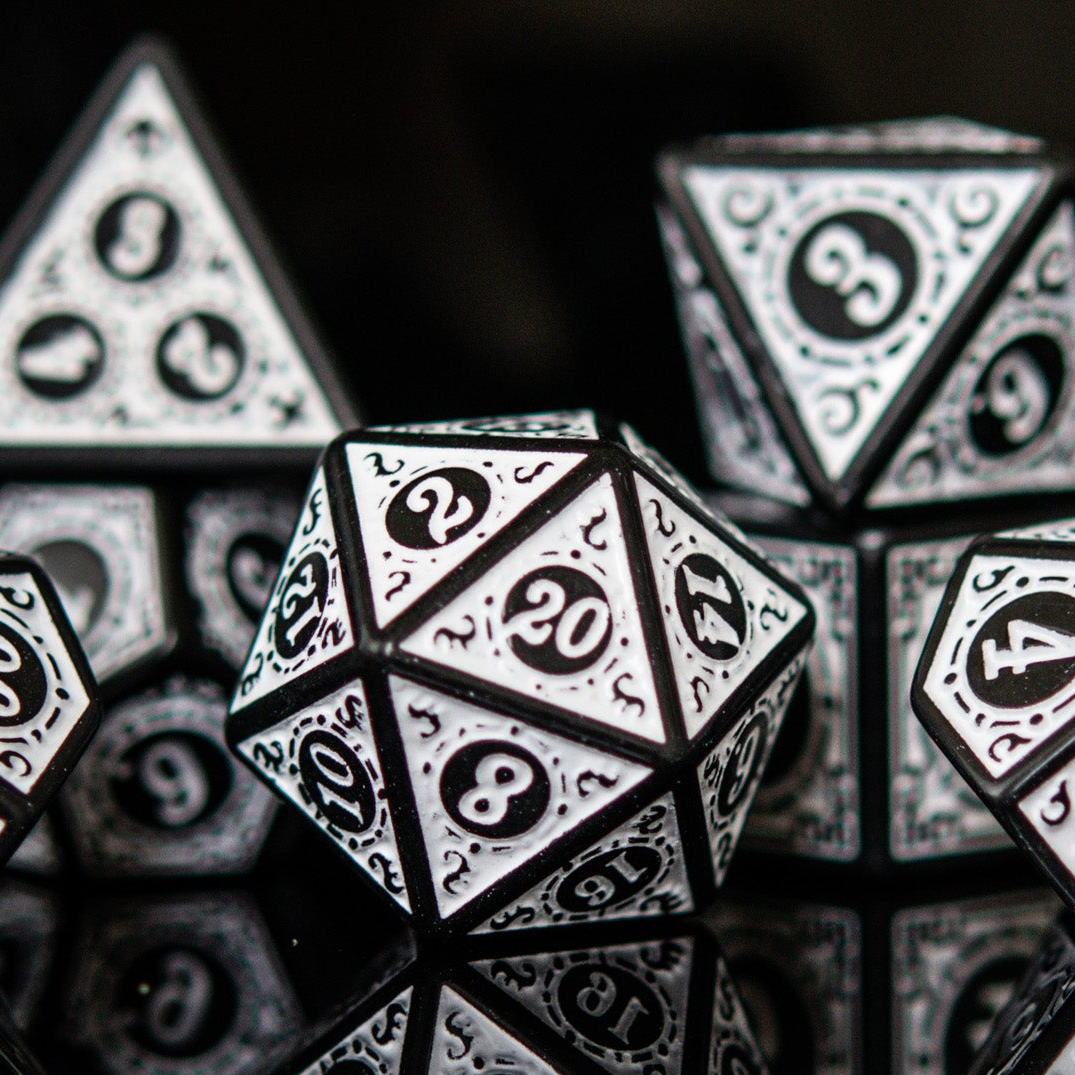 A set of white acrylic ttrpg dice with black engravings, displayed on a reflective surface.