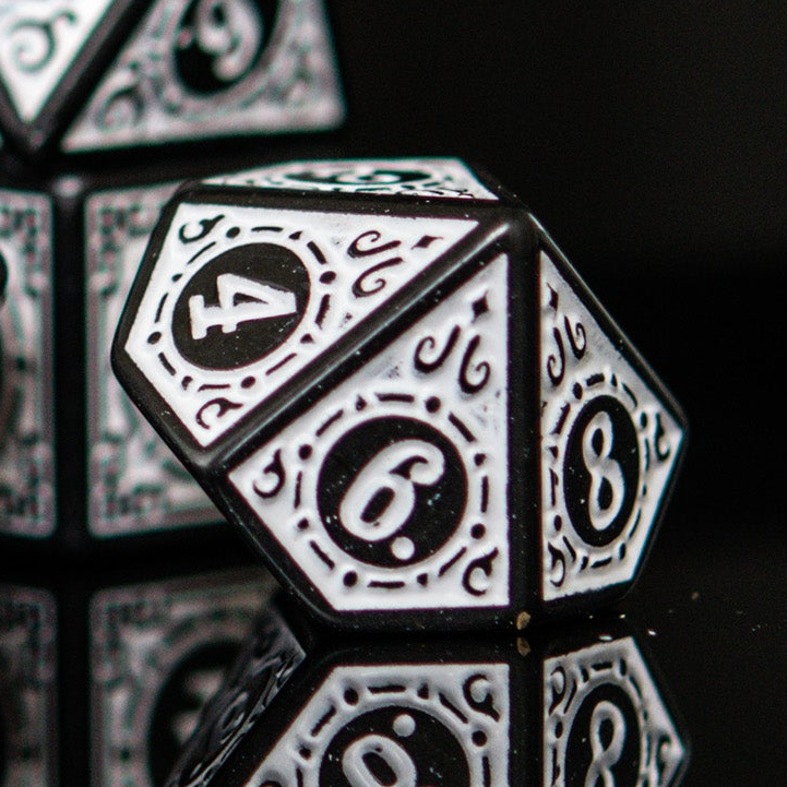 Close-up of black and white polyhedral dnd ttrpg dice with numbers on a dark background