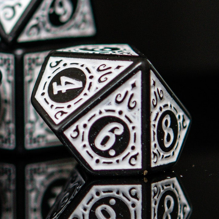 Close-up of black and white polyhedral dnd ttrpg dice with numbers on a dark background