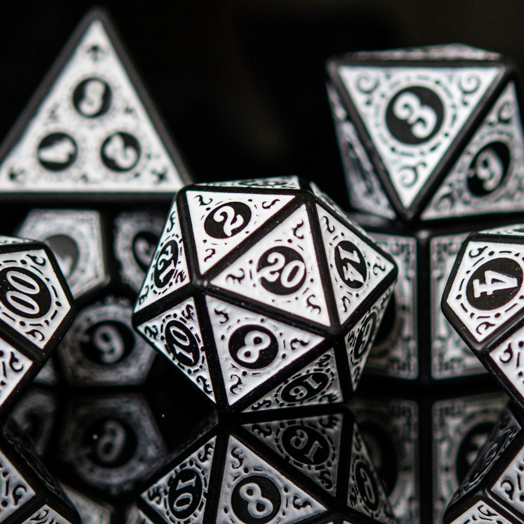 Close-up of polyhedral dice with black and white numbering on a reflective surface.