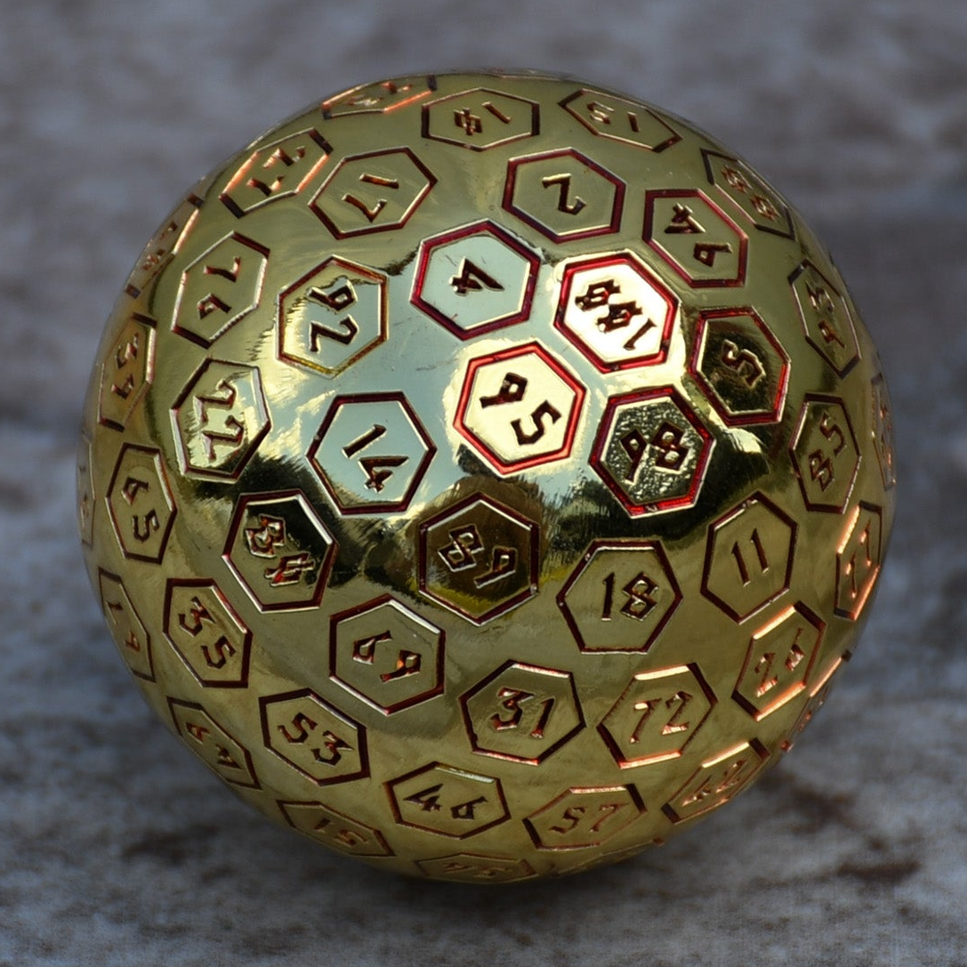 A red and gold oversized metal D100 dice with engraved numbers on a textured background.