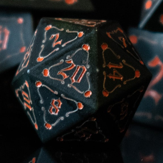 A set of black aluminum metal dice with orange engraved numbers, displayed in front of a pumpkin-shaped silhouette. The dice include a D4, D6, D8, two D10s, D12, and D20.