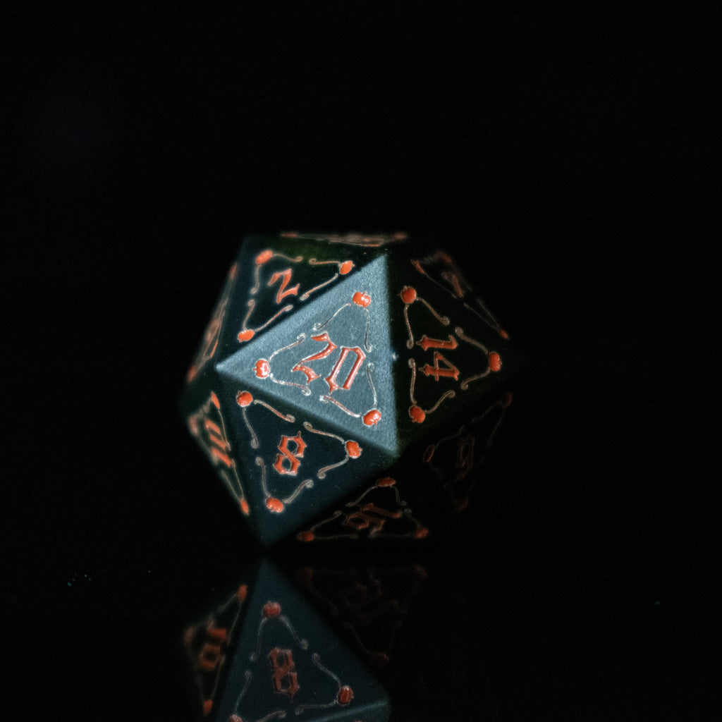 A set of black aluminum metal dice with orange engraved numbers, displayed in front of a pumpkin-shaped silhouette. The dice include a D4, D6, D8, two D10s, D12, and D20.