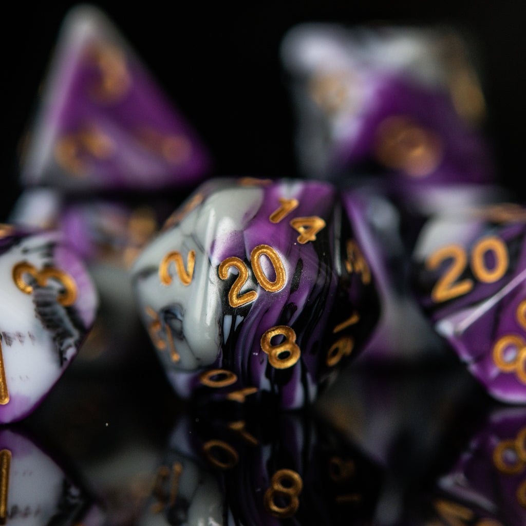 A set of acrylic dnd dice with purple, white, and black colors, featuring engraved gold numbers, arranged on a reflective surface for playing wargaming tabletop gaming and board games