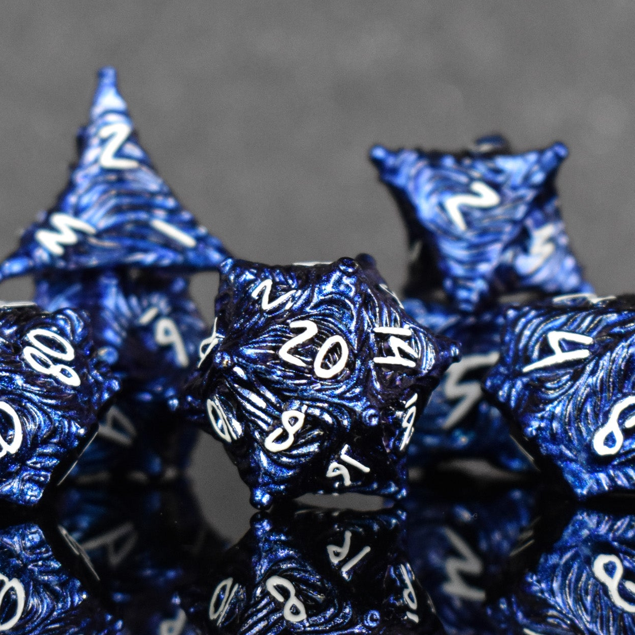 a set of dark blue metal dice with vortex swirls and a white font
